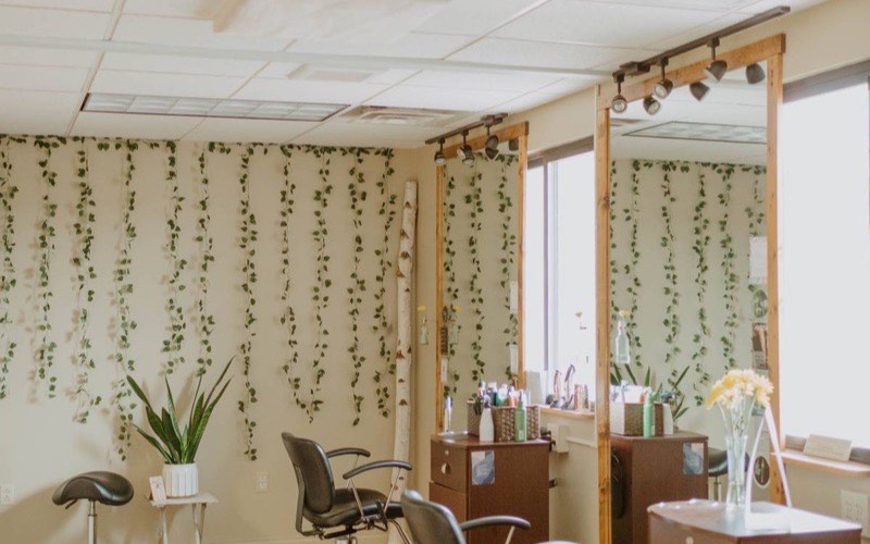 The salon floor at J. Jukuri with styling chairs, mirrors and trailing greenery on the walls