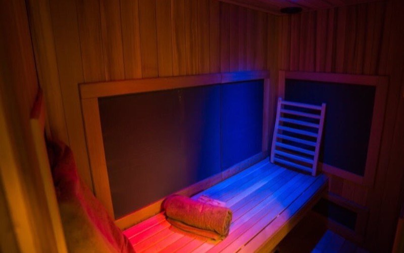 The cedar-lined interior of the full spectrum infrared sauna lit with chromotherapy colour
