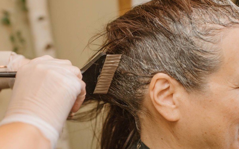 A stylist applying colour with a brush during a foil highlight service