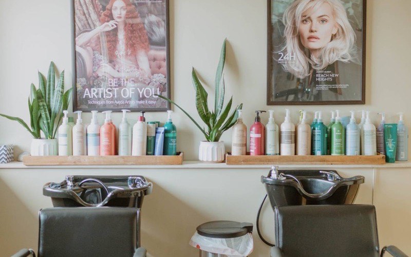 Shampoo bowls and a shelf of professional haircare products in the salon