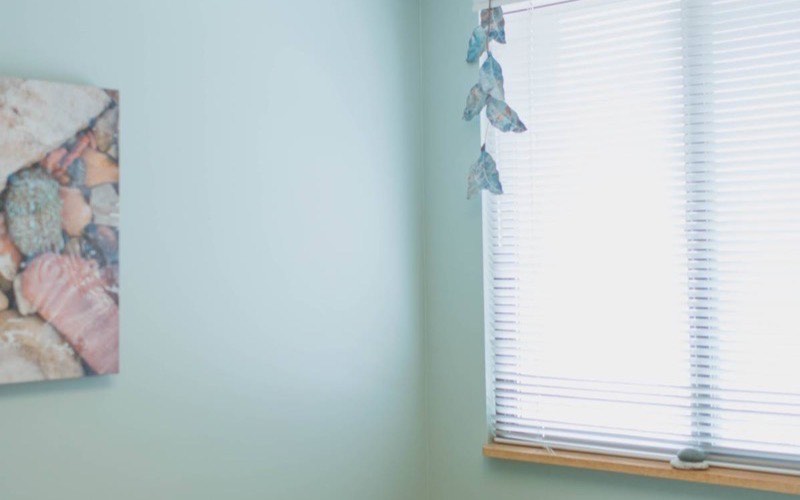 A quiet treatment room at J. Jukuri with soft blue walls and natural light
