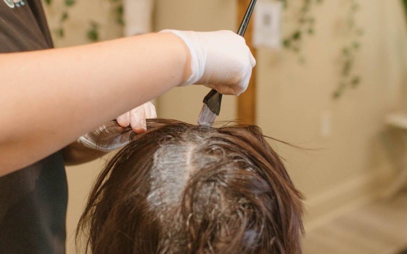 A stylist painting colour through sectioned hair during a highlight service