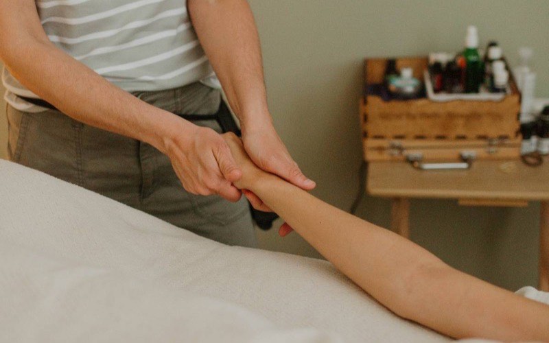A therapist applying slow, sustained pressure along a client's forearm
